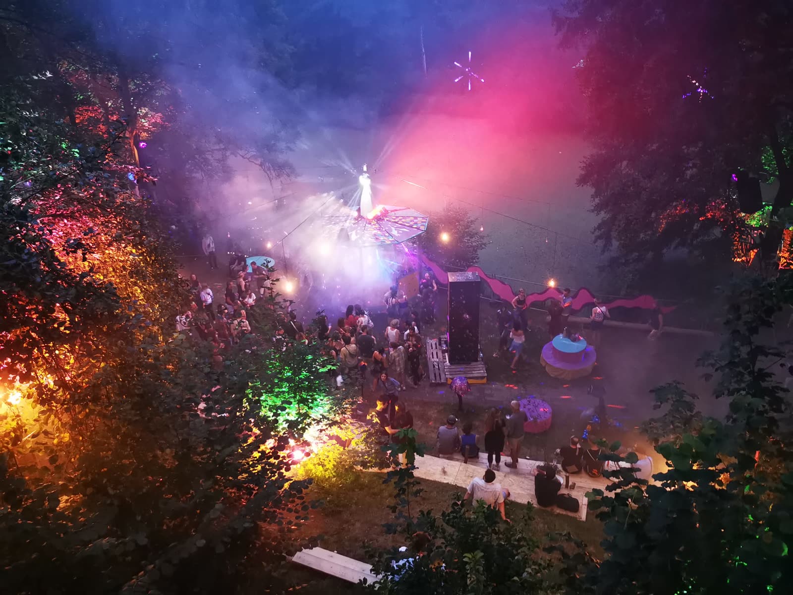 Eine Bühne im Wald bei Nacht, bunte Scheinwerfer im Rauch