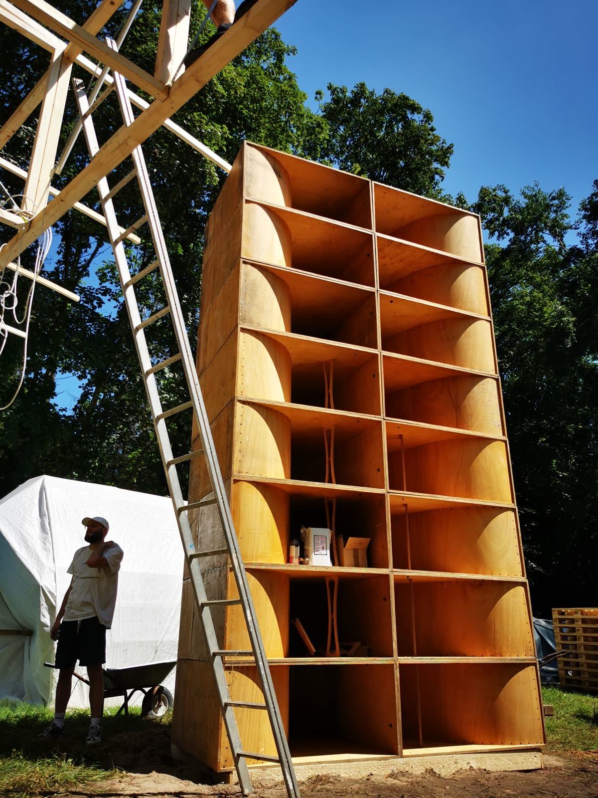Ein hoher Lautsprecherturm aus Holz unter Bäumen